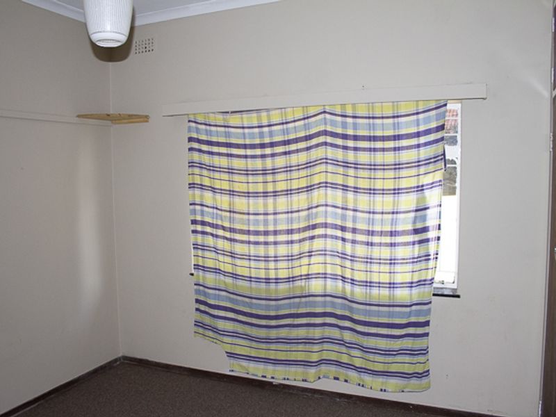 An empty bedroom featuring built-in cupboards, neutral wall paint, and carpet flooring, offering a blank canvas for potential updates and personalization.
