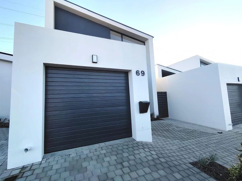 Modern residential facade featuring a dark sectional garage door, paved driveway, and clean architectural lines.