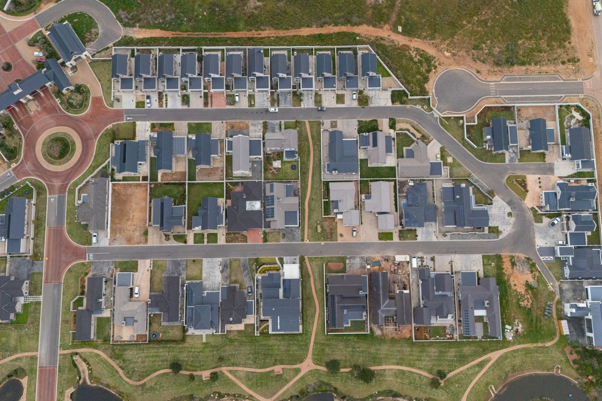 An aerial view of a modern townhouse estate featuring multiple residential units, paved road networks, and landscaped common areas.