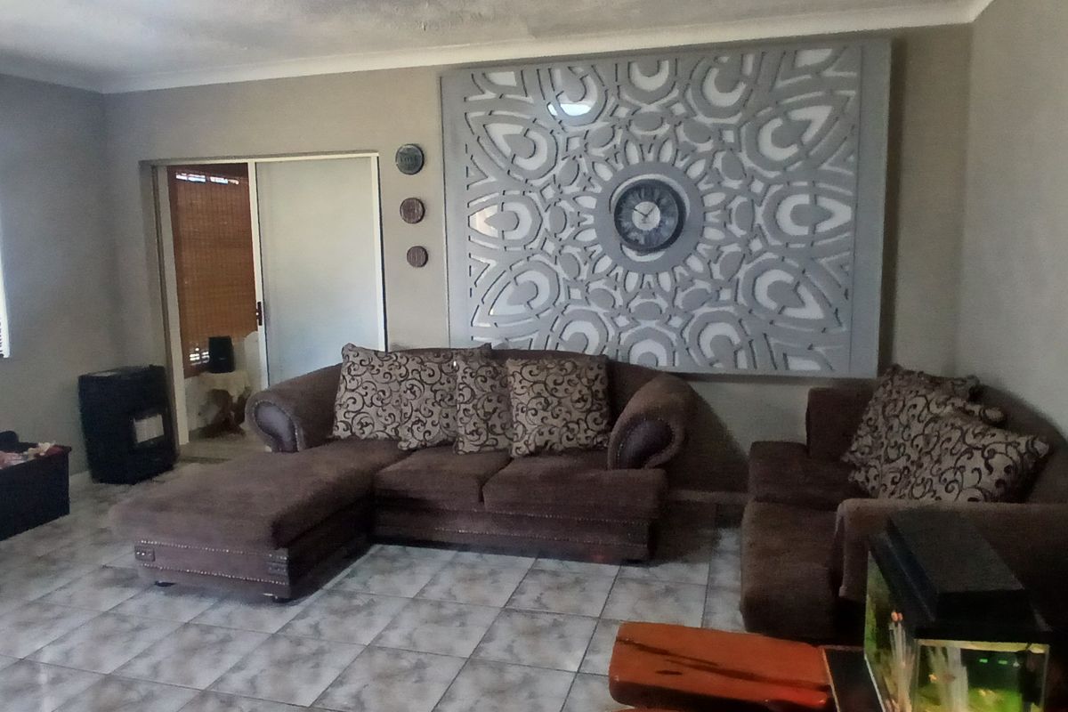 A living room featuring tiled flooring, a sliding door, and a large decorative wall panel.