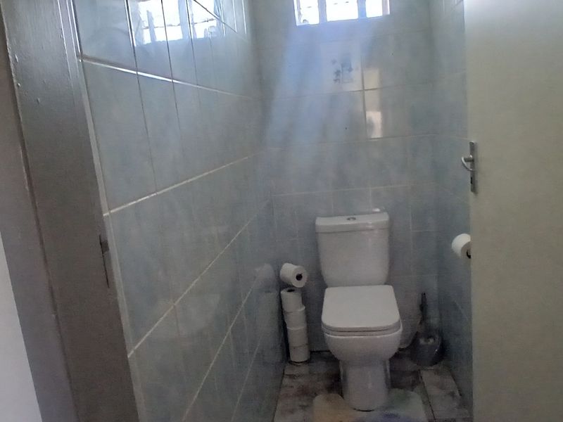 A compact, functional bathroom featuring tiled walls and floor with a standard toilet suite.