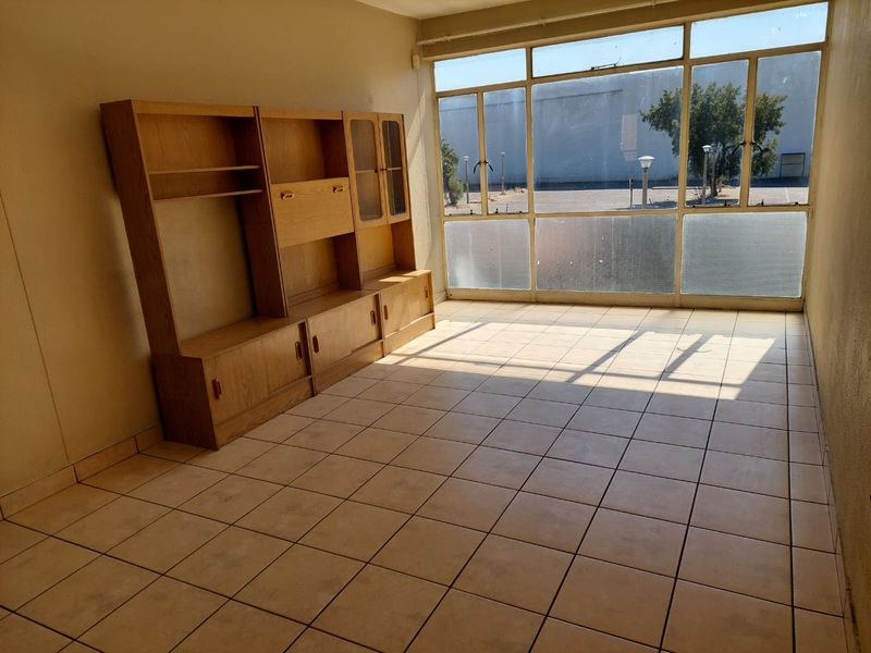 A living area featuring large windows providing natural light and tiled flooring throughout.