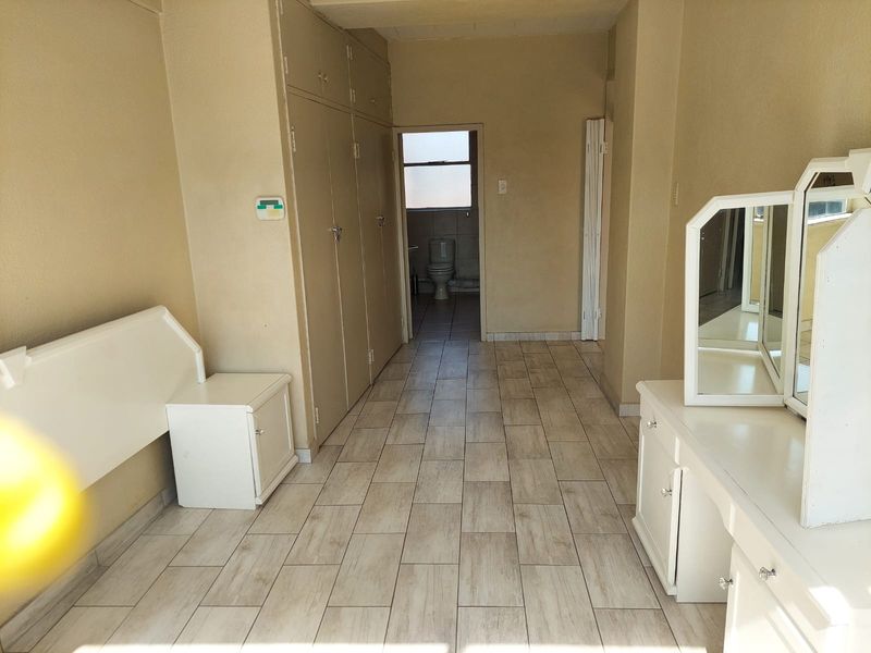 A bedroom featuring tiled flooring and built-in cupboards, with direct access to an en-suite bathroom.