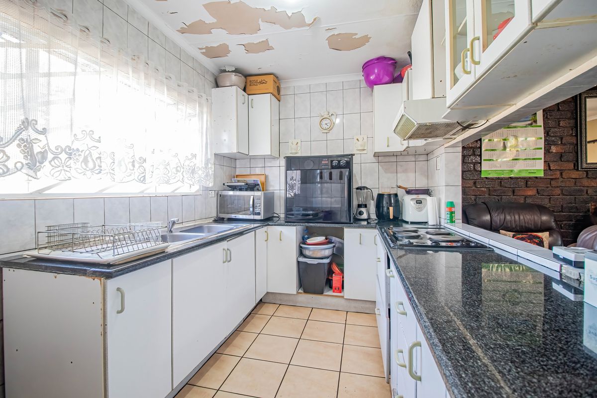A functional kitchen featuring granite countertops, built-in cabinetry, and ceramic tile flooring, currently requiring ceiling repairs and cosmetic updates.