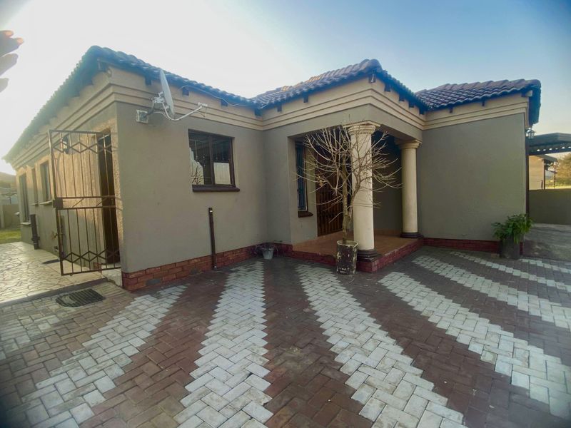 Front elevation of a residential house featuring a covered entrance porch with decorative columns and a patterned brick paved driveway.