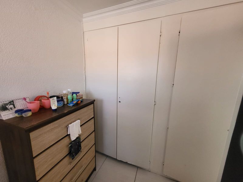 A bedroom featuring built-in cupboards with white doors and tiled flooring.