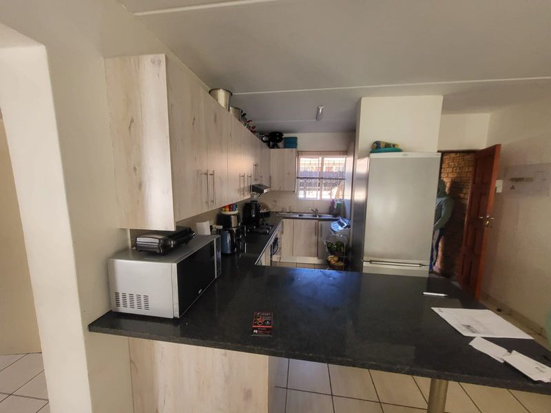 A functional kitchen featuring light wood-look cabinetry, dark granite countertops, and tiled flooring, providing a practical workspace with an integrated breakfast bar.