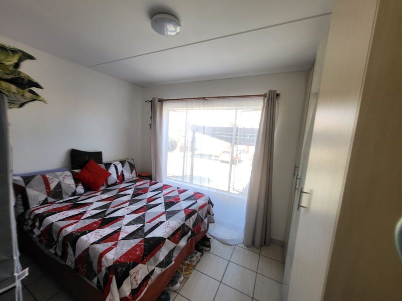 A functional bedroom featuring tiled flooring and built-in cupboards, providing essential storage space and a neutral foundation for personal styling.