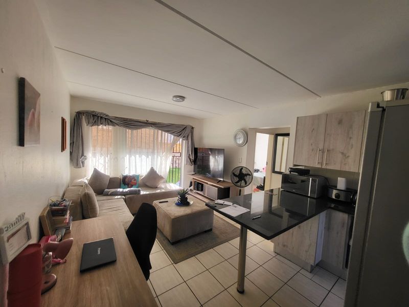 Open-plan living area featuring tiled flooring, a modern kitchen with breakfast bar, and direct access to the outdoor space through a sliding door.
