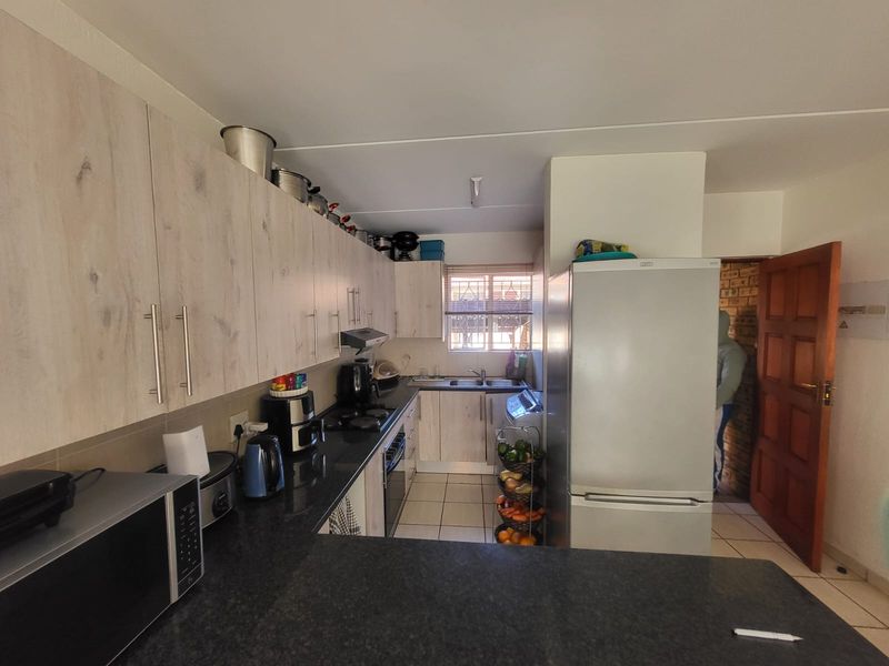 Functional kitchen featuring light wood-look cabinetry, dark granite countertops, built-in oven, hob, and extractor fan with tiled flooring.