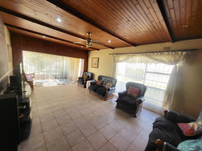 Spacious living room featuring a timber-clad ceiling with recessed lighting, tiled flooring, and large sliding glass doors providing access to the outdoor area.