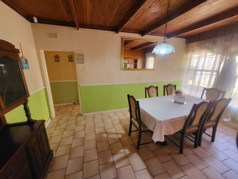 Dining room featuring exposed timber beam ceilings, ceramic tile flooring, and a dado rail finish.