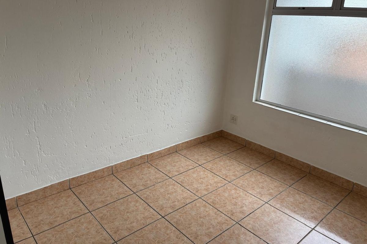 A vacant bedroom featuring neutral textured walls and tiled flooring, providing a clean and versatile space ready for personalization.