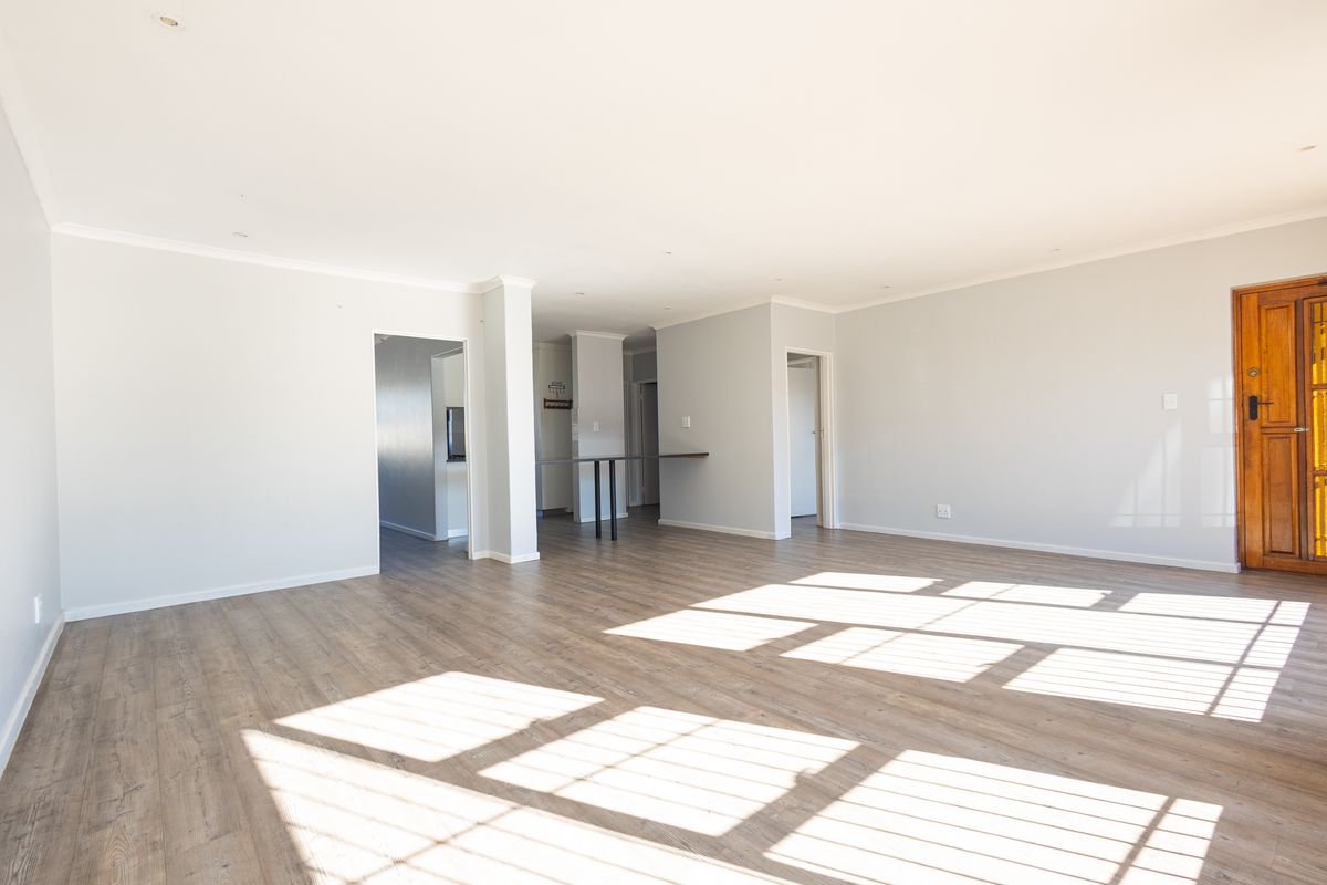 A spacious, light-filled open-plan living area featuring modern laminate flooring, recessed lighting, and a neutral color palette, ready for personalization.