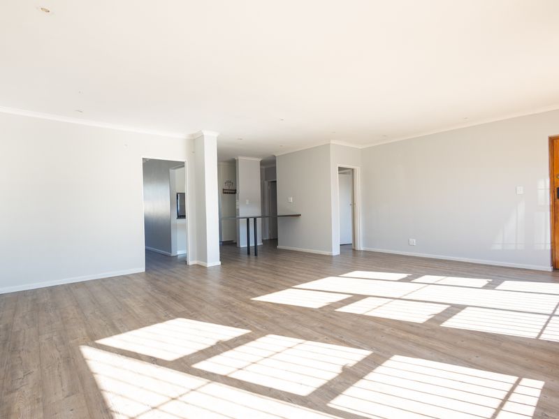 A spacious, light-filled open-plan living area featuring modern laminate flooring, recessed lighting, and a neutral color palette, ready for personalization.