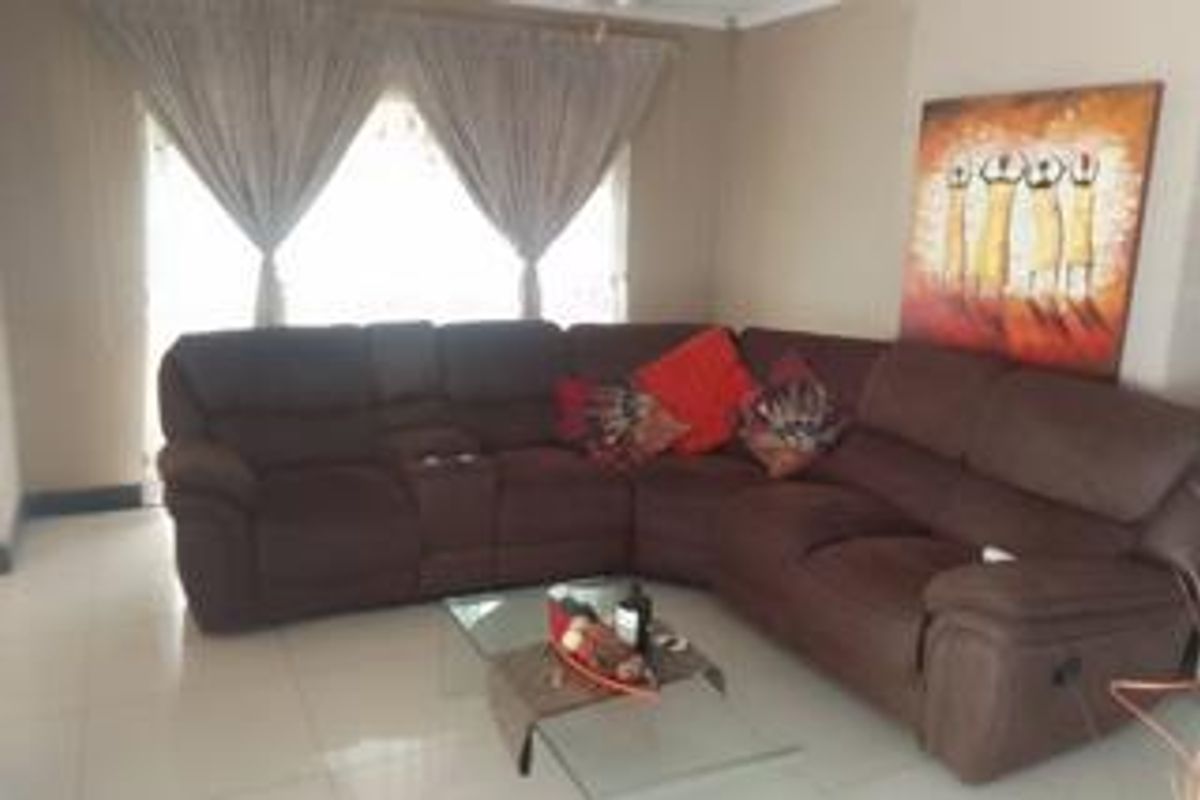 A living room featuring tiled flooring and large windows with curtain rails, providing a functional and comfortable space for relaxation.