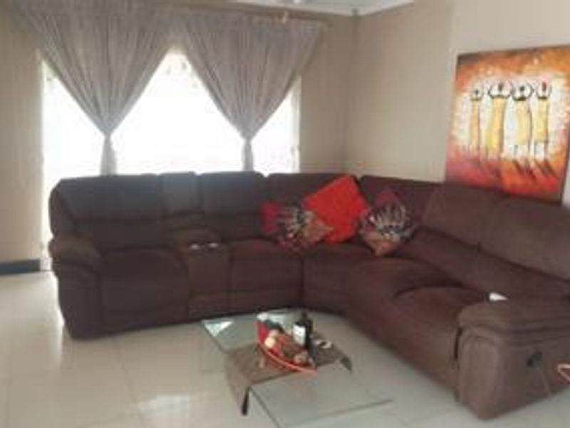 A living room featuring tiled flooring and large windows with curtain rails, providing a functional and comfortable space for relaxation.