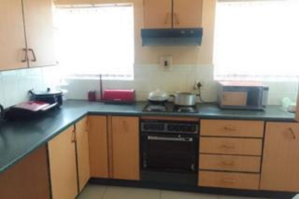 A functional kitchen featuring laminate cabinetry, dark countertops, a built-in oven with hob, and an extractor fan, offering a practical layout for daily use.