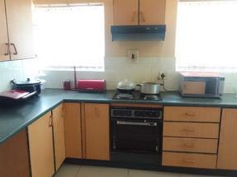 A functional kitchen featuring laminate cabinetry, dark countertops, a built-in oven with hob, and an extractor fan, offering a practical layout for daily use.