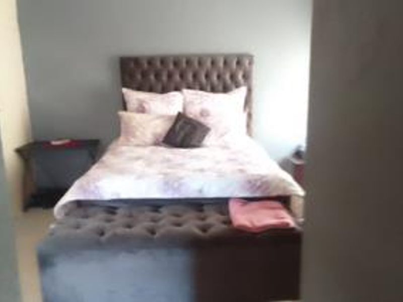 A bedroom featuring a tufted headboard and neutral wall paint, captured in a low-quality, slightly blurry photograph.