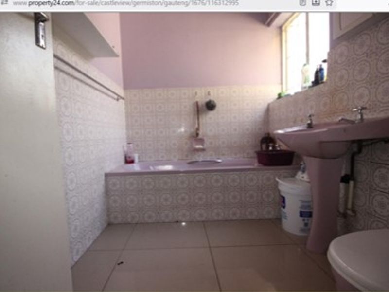 A dated bathroom featuring a built-in bathtub and pedestal basin with original wall tiling, offering potential for a modern renovation.