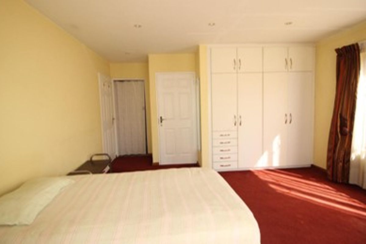 A bedroom featuring built-in cupboards, recessed lighting, and carpeted flooring.