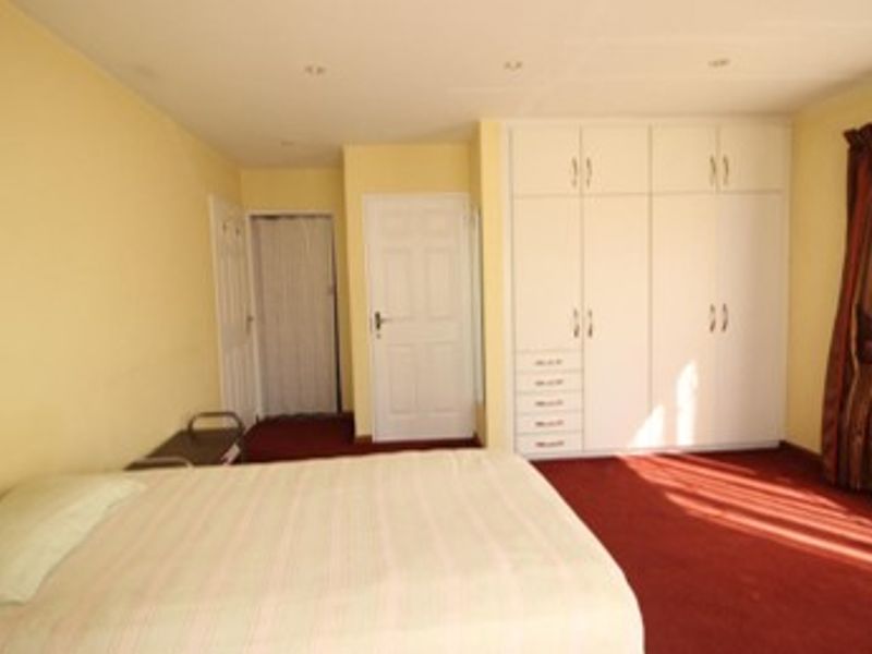 A bedroom featuring built-in cupboards, recessed lighting, and carpeted flooring.