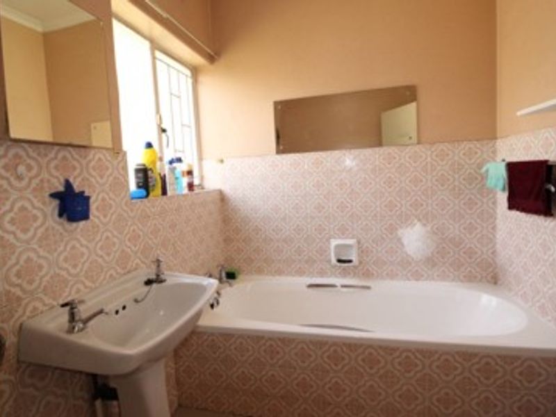 A functional bathroom featuring a pedestal basin and a built-in bathtub with decorative tiled splashbacks.