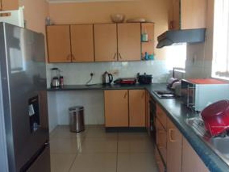 A functional kitchen featuring laminate cabinetry, tiled flooring, and a tiled backsplash, offering a practical layout for daily meal preparation.