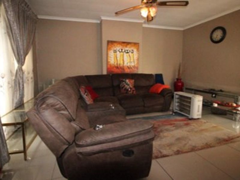 A living room featuring tiled flooring, a ceiling fan, and neutral wall finishes.