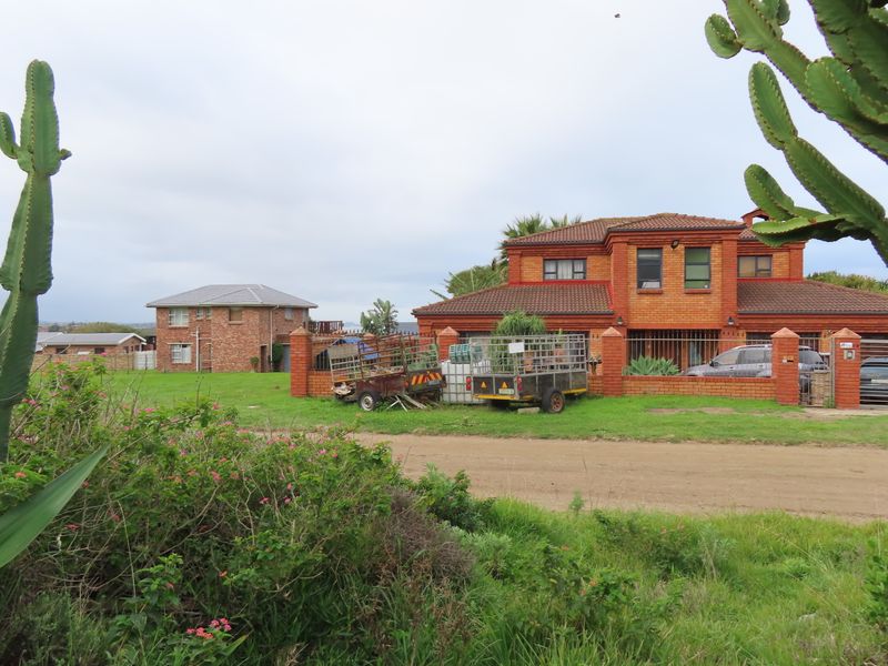 Front view of a two-story brick residential property with a tiled roof, perimeter wall, and gated driveway access.