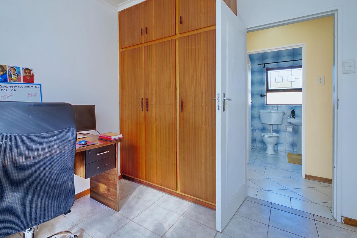 Bedroom featuring built-in wooden wardrobes, tiled flooring, and direct access to an en-suite bathroom with blue wall tiles.