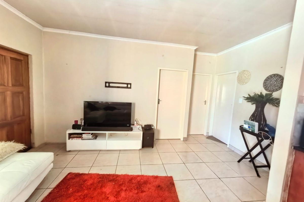 A living room featuring tiled flooring and neutral wall finishes, providing a functional space with multiple internal door access points.