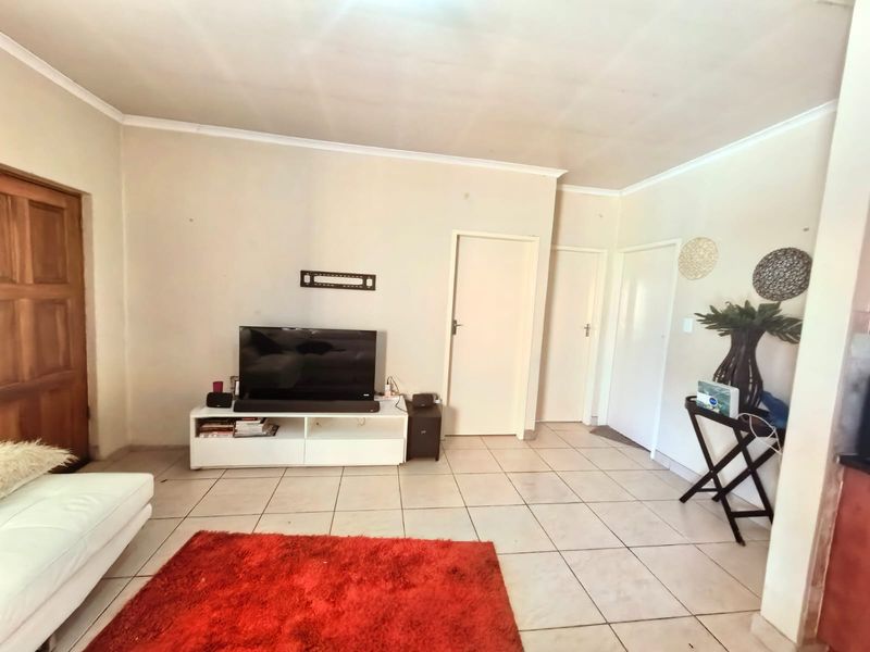 A living room featuring tiled flooring and neutral wall finishes, providing a functional space with multiple internal door access points.