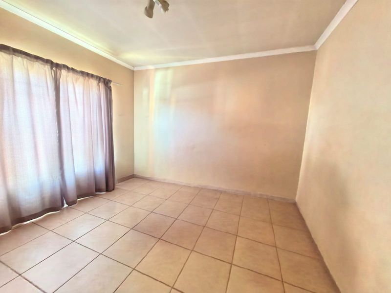 An empty living room featuring neutral tiled flooring and curtain tracks, providing a blank canvas for interior design.