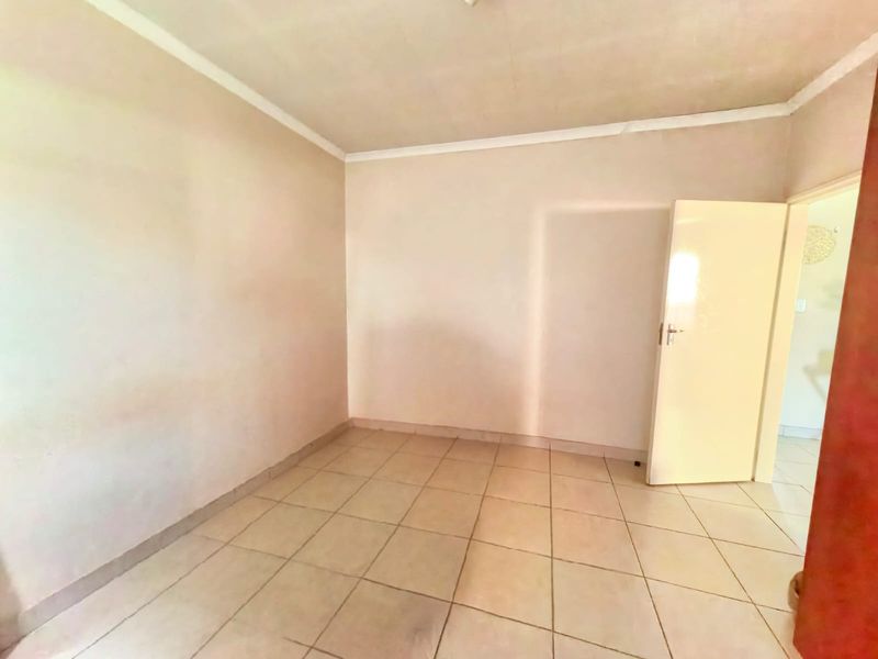 An empty bedroom featuring tiled flooring and neutral walls, providing a blank canvas for potential interior design and staging.