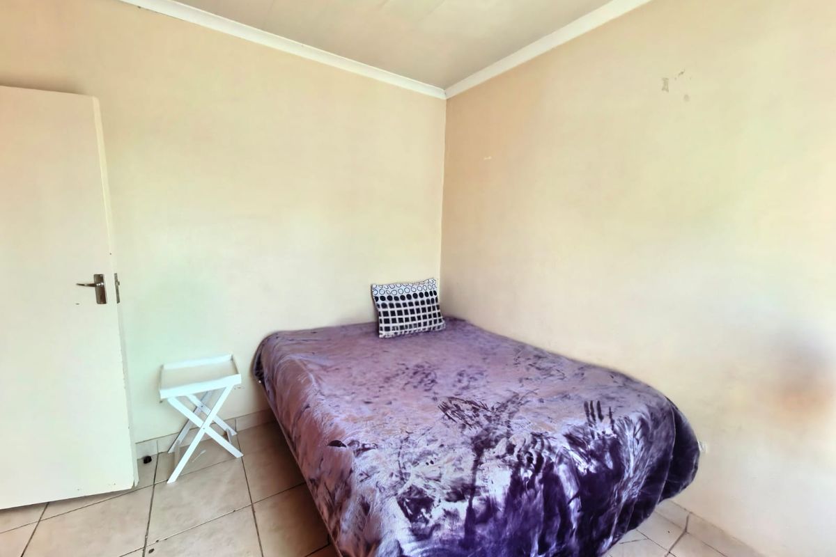 A compact bedroom featuring tiled flooring and neutral wall finishes, offering a functional space ready for cosmetic updates and personalization.