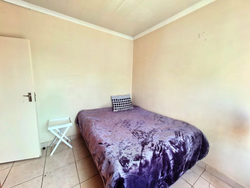 A compact bedroom featuring tiled flooring and neutral wall finishes, offering a functional space ready for cosmetic updates and personalization.