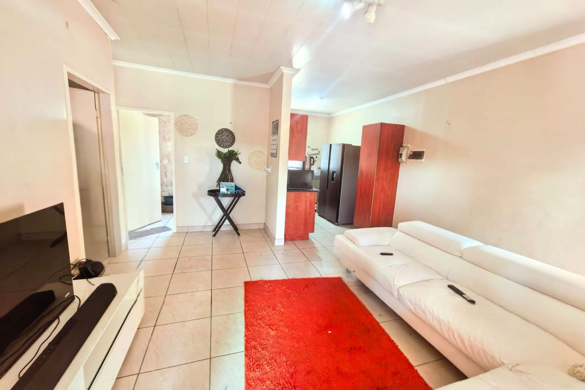 Open plan living area featuring tiled flooring and a connected kitchen space, offering a functional layout for modern apartment living.