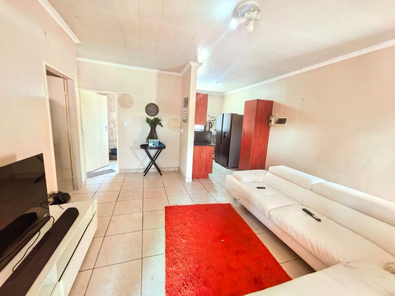 Open plan living area featuring tiled flooring and a connected kitchen space, offering a functional layout for modern apartment living.