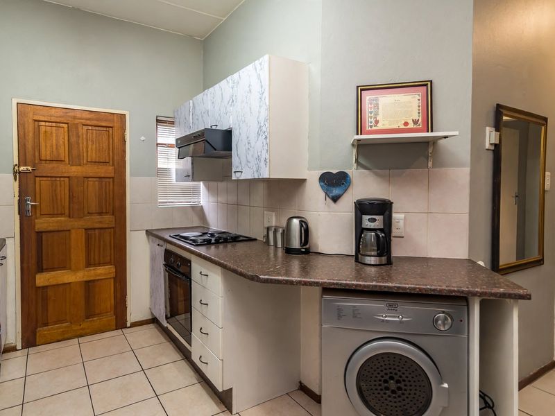 A functional kitchen featuring built-in cabinetry, a hob, oven, extractor fan, and tiled flooring, offering a practical layout for daily use.