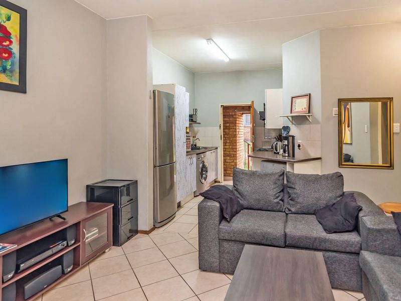 Open-plan living area featuring tiled flooring and a functional kitchen space with built-in cabinetry and countertops.