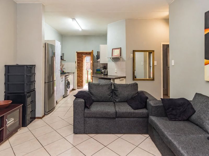 Open-plan living area featuring tiled flooring and a functional kitchen space with built-in cabinetry and laundry plumbing connections.
