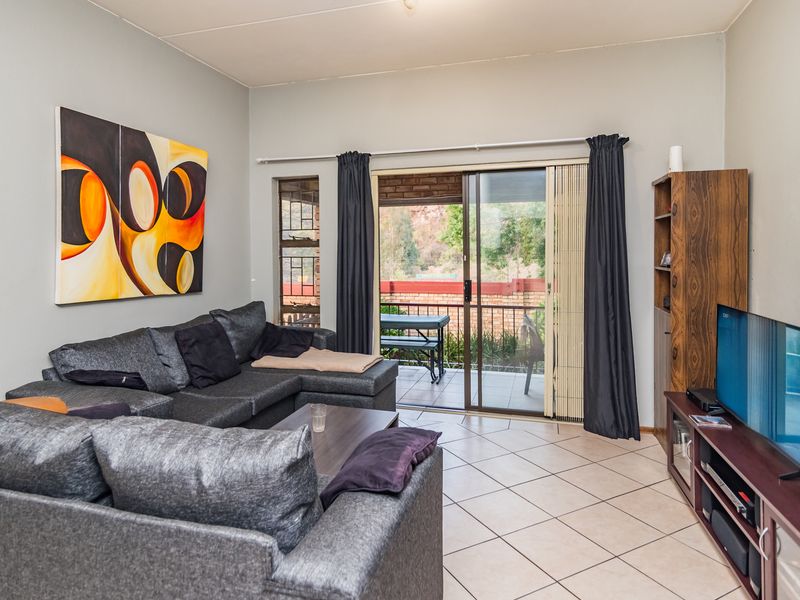 A living room featuring ceramic tile flooring and a sliding glass door providing access to an outdoor patio area.