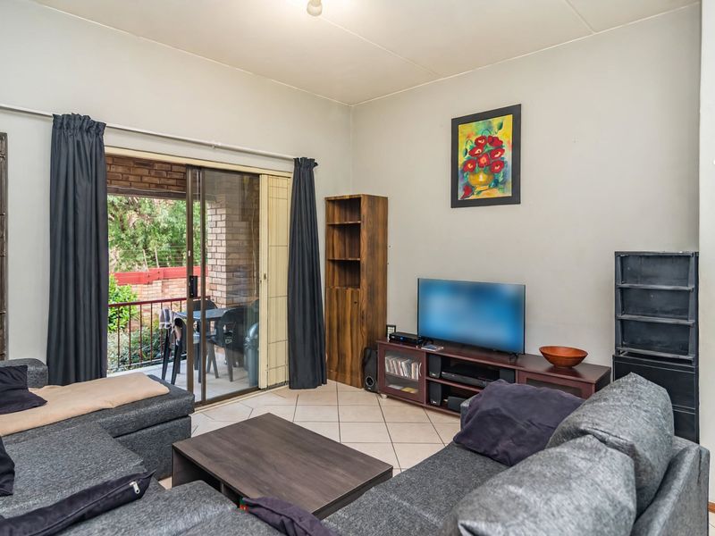 A functional living room featuring ceramic floor tiles and a sliding glass door that provides access to an outdoor balcony area.