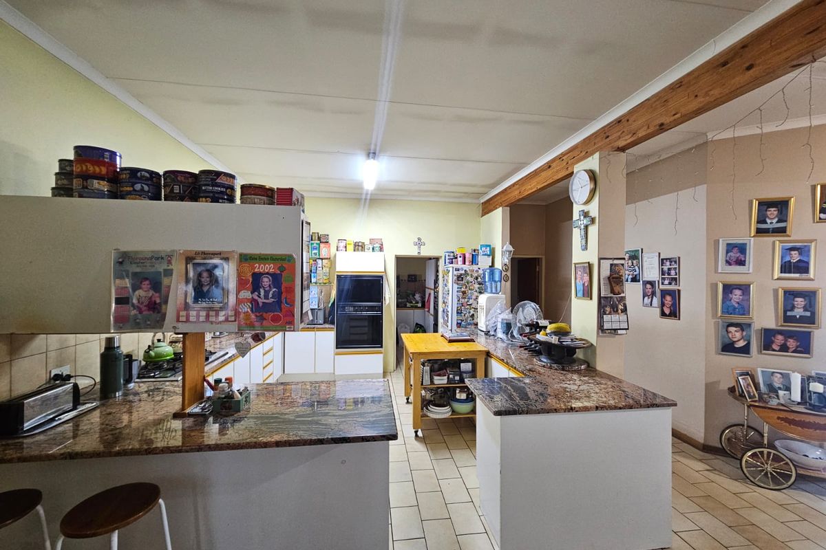 Spacious kitchen featuring granite countertops, a breakfast bar, built-in oven, and tiled flooring, offering a functional layout with potential for modern updates.
