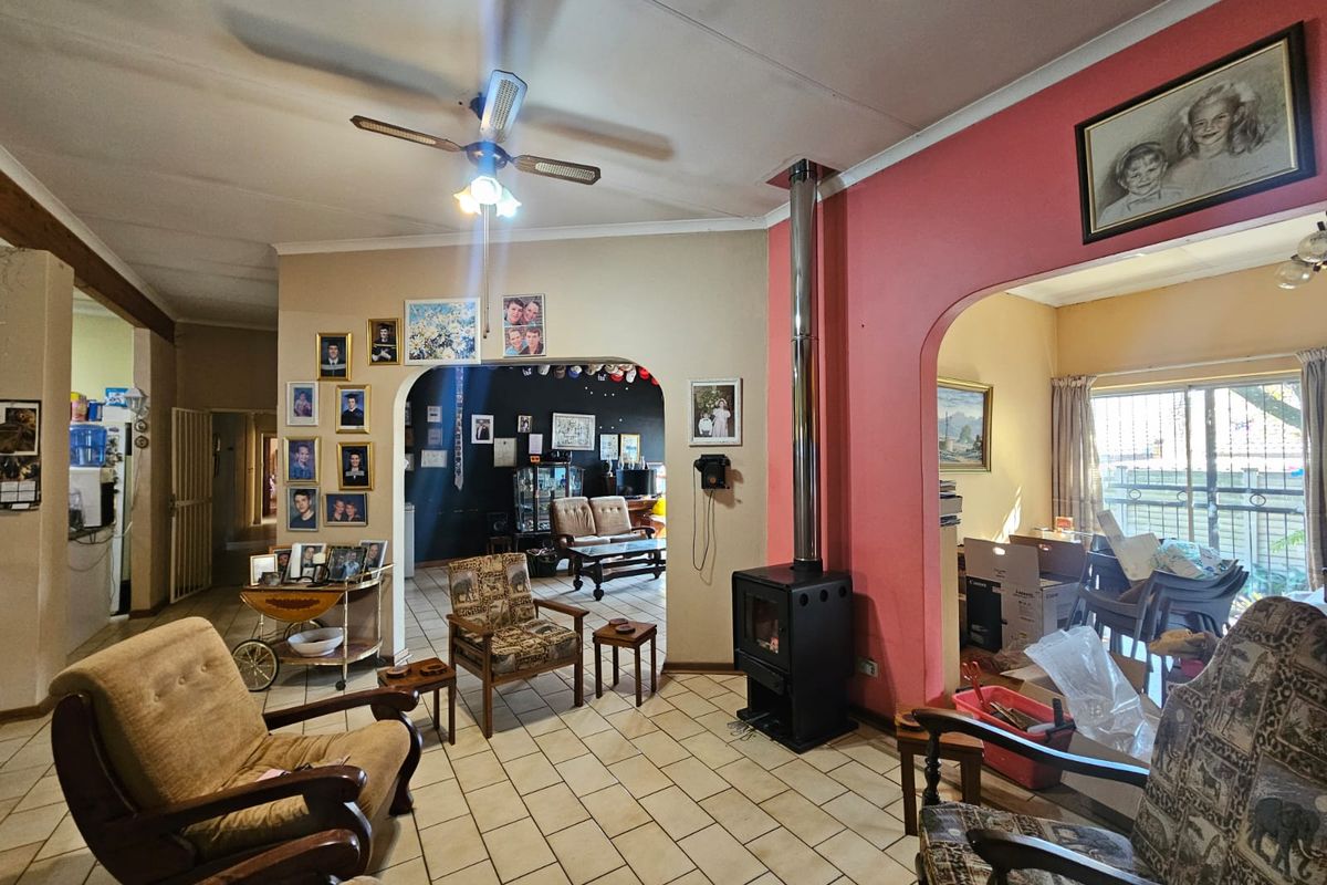 Spacious living area featuring a wood-burning fireplace, tiled flooring, and arched architectural details connecting to adjacent rooms.
