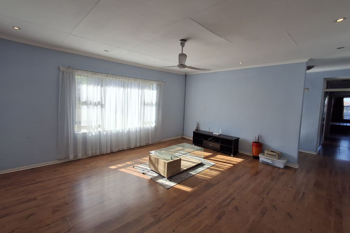Spacious living room featuring warm laminate flooring, a ceiling fan, and recessed lighting, offering a bright and open area for relaxation.