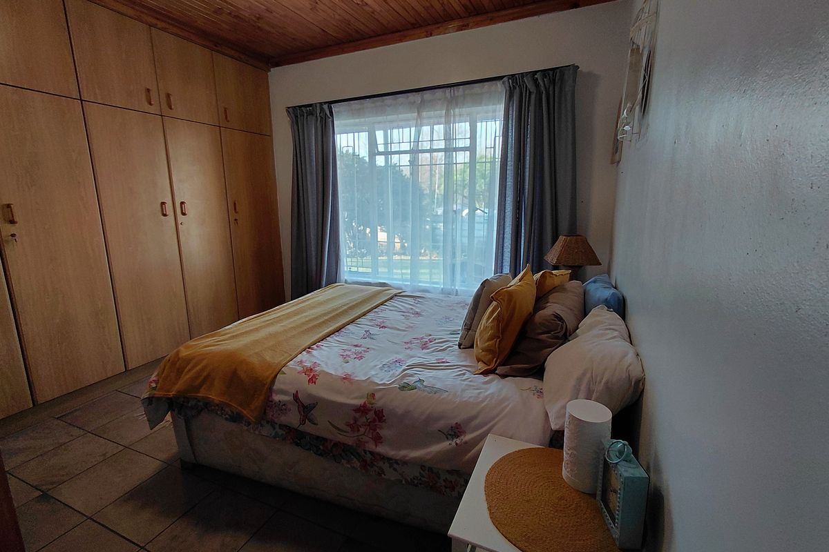 A bedroom featuring built-in wooden cupboards, a timber-clad ceiling, and tiled flooring, providing a functional and cozy living space.