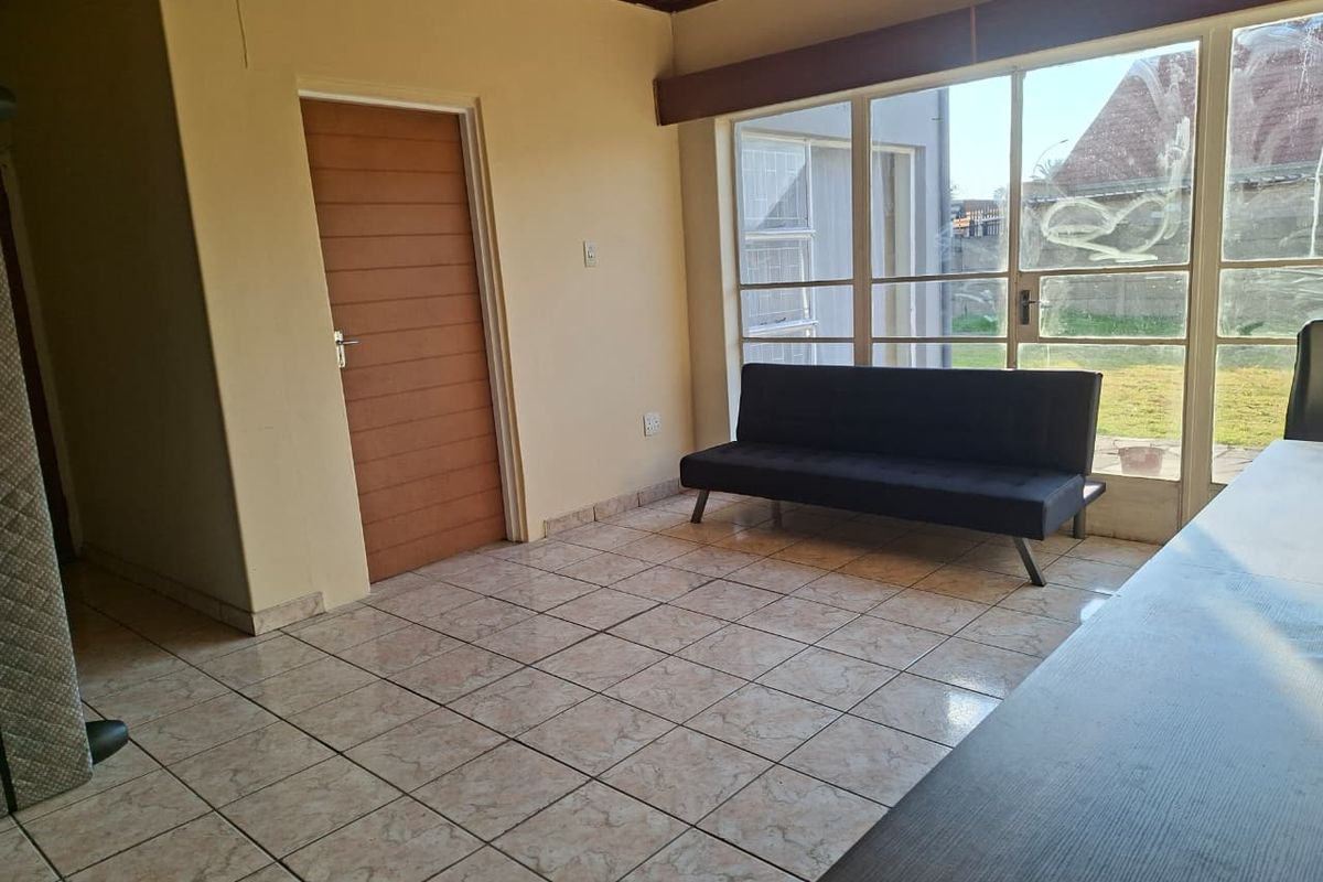 A living area featuring tiled flooring, a timber ceiling, and large glass sliding doors providing natural light and access to the garden.